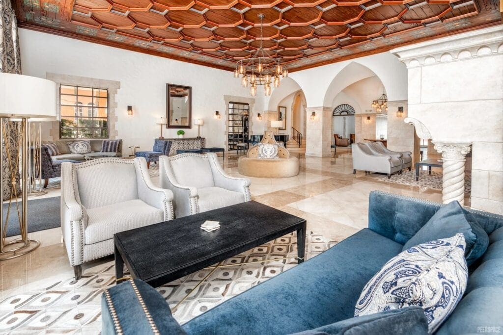 A 1920s art deco-style hotel lobby with ornate ceilings, chandeliers, velvet couches and gold and marble accents