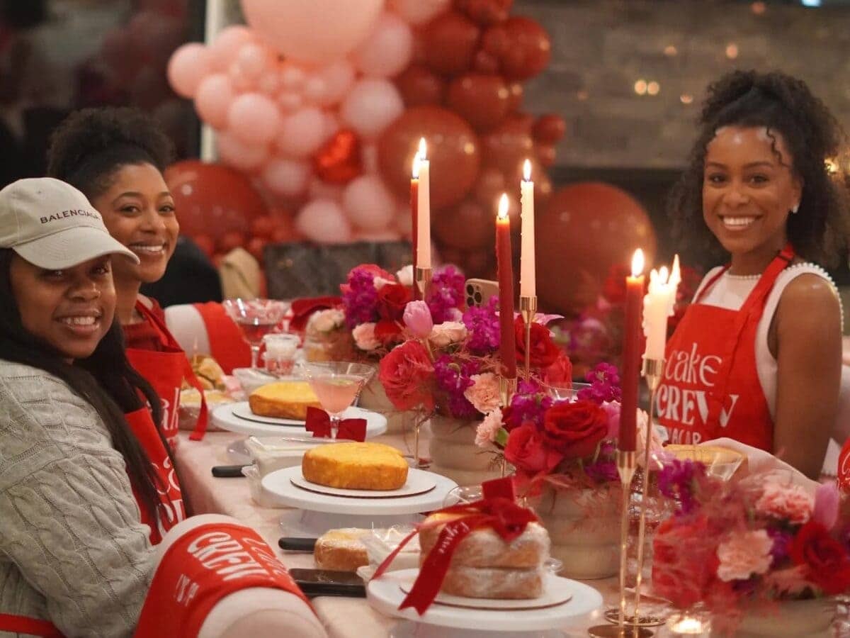Galentines cake decorating class with friends sitting at table in aprons