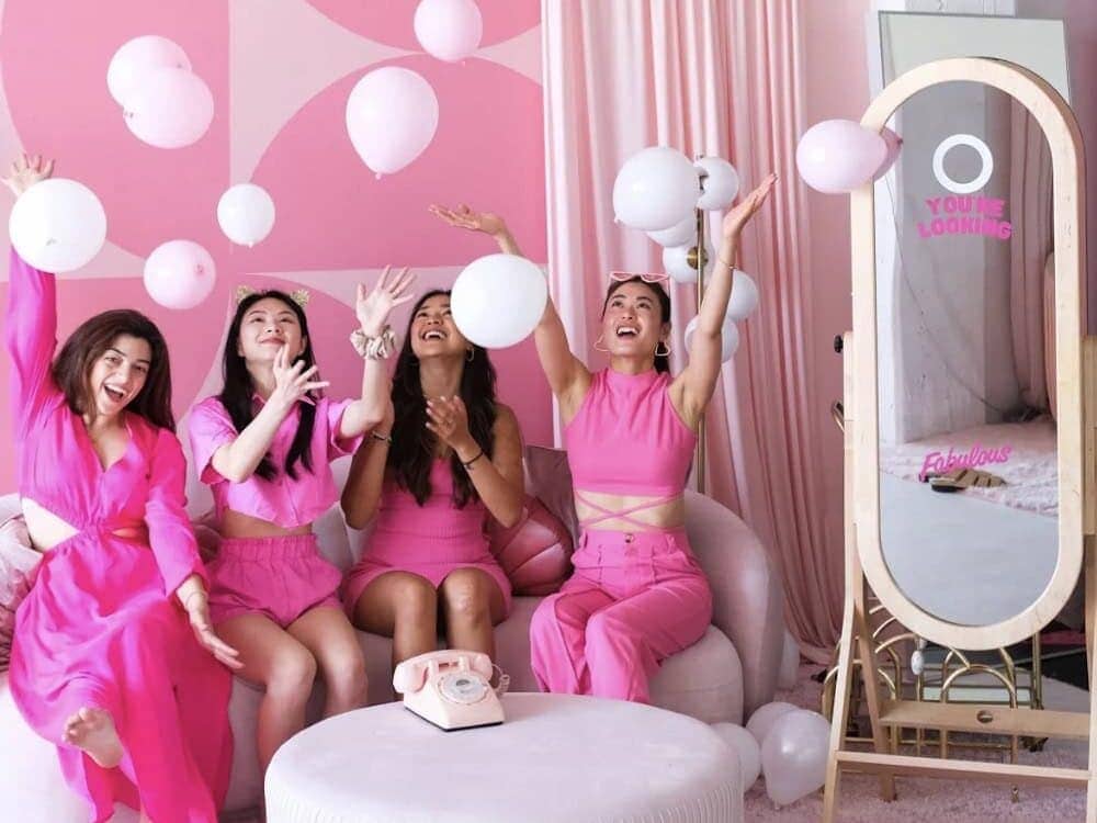 Four friends in pink Galentines outfits throwing balloons