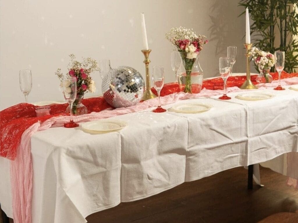 Galentine's party table with disco ball, flowers, and plates