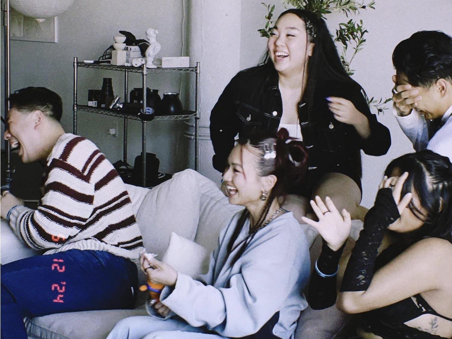 Friends on couch laughing at a PowerPoint party