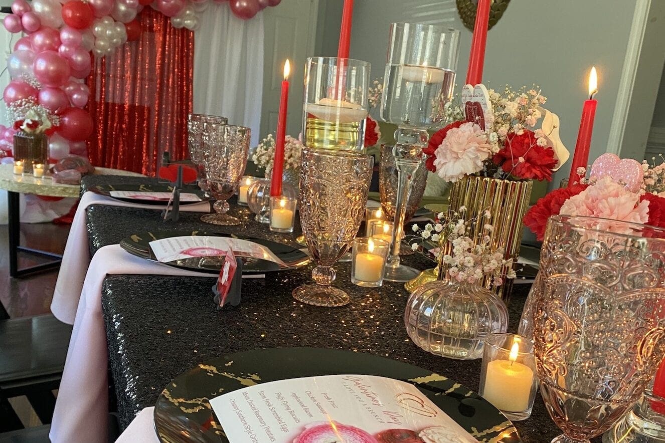 At-home Galentine's day brunch with glasses, menu, red candles, and pink balloons
