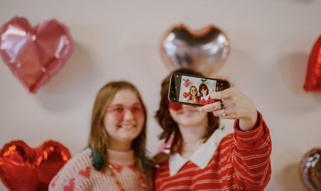 Two friends in Galentines theme sweaters taking a selfie