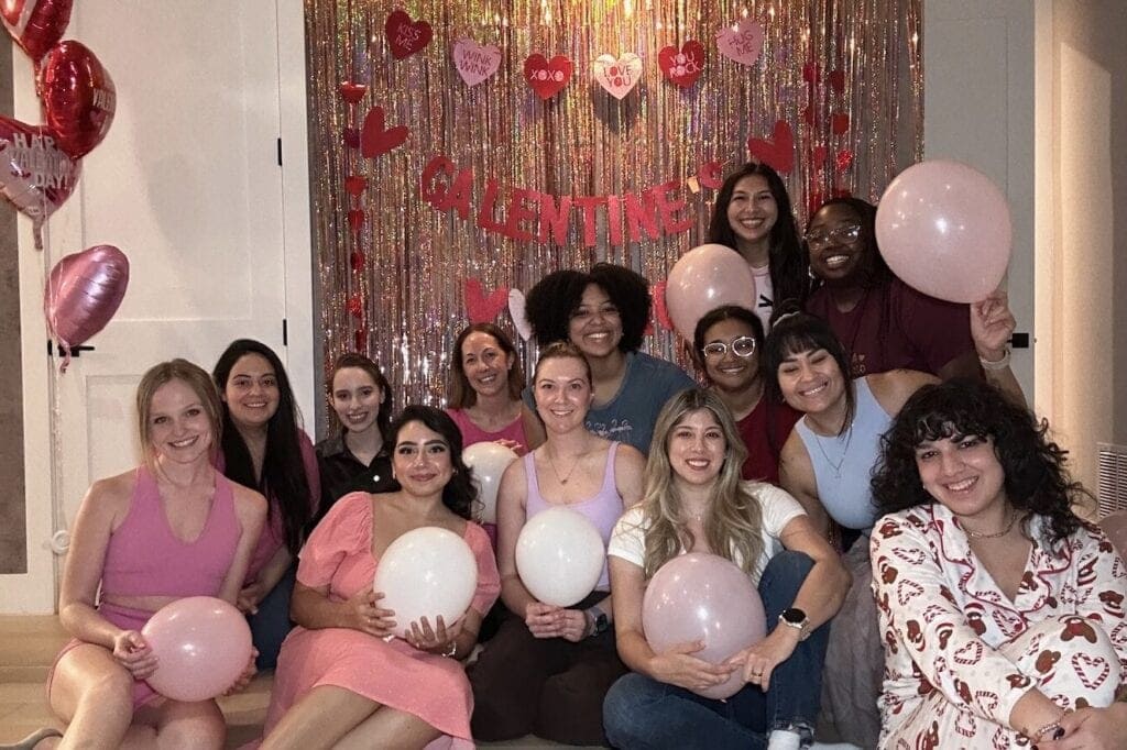 Group of friends posed in front of Galentine's day backdrop with balloons