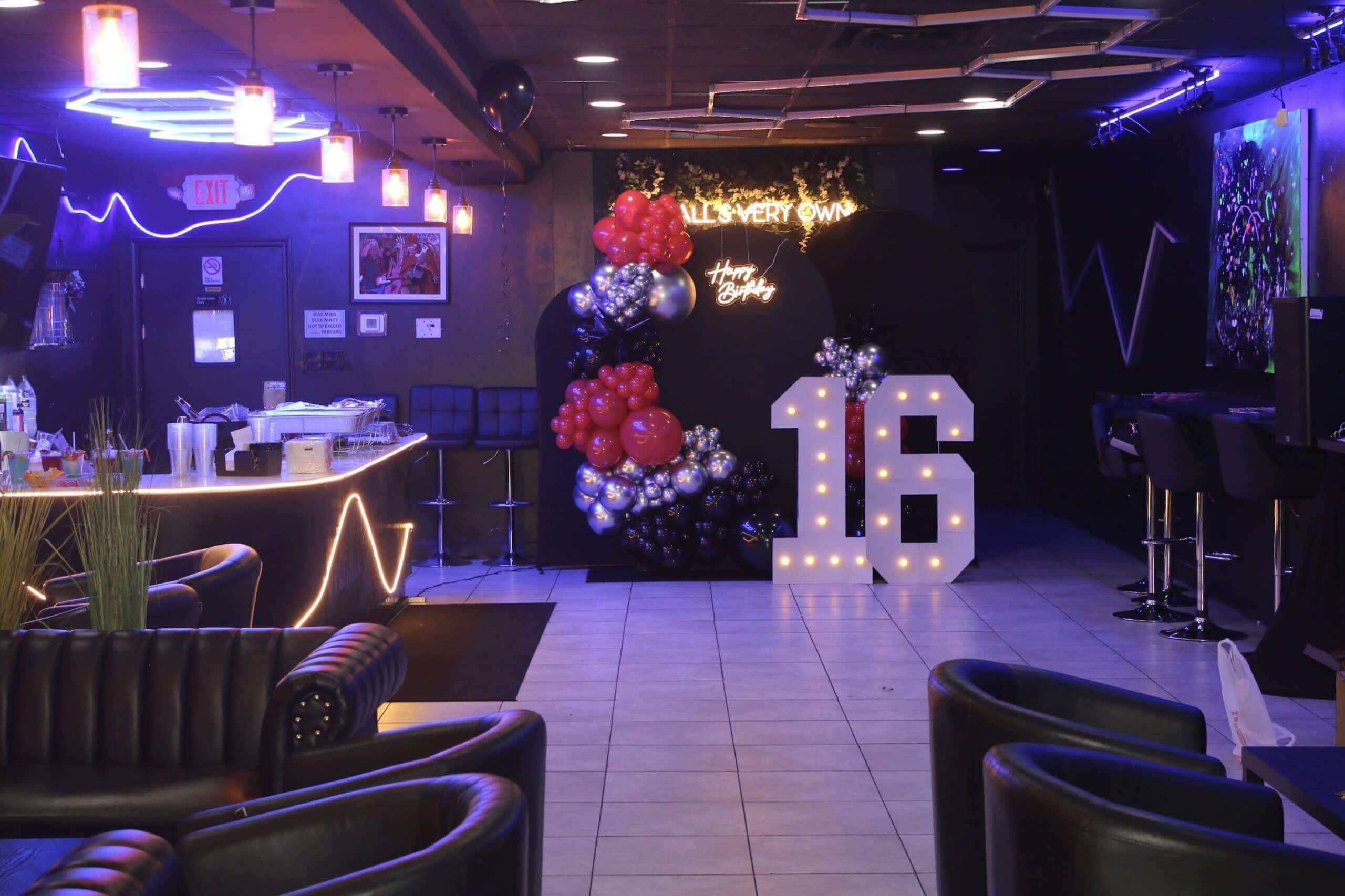Teen birthday party venue with large numbers 16, neon signs, balloons, and chairs
