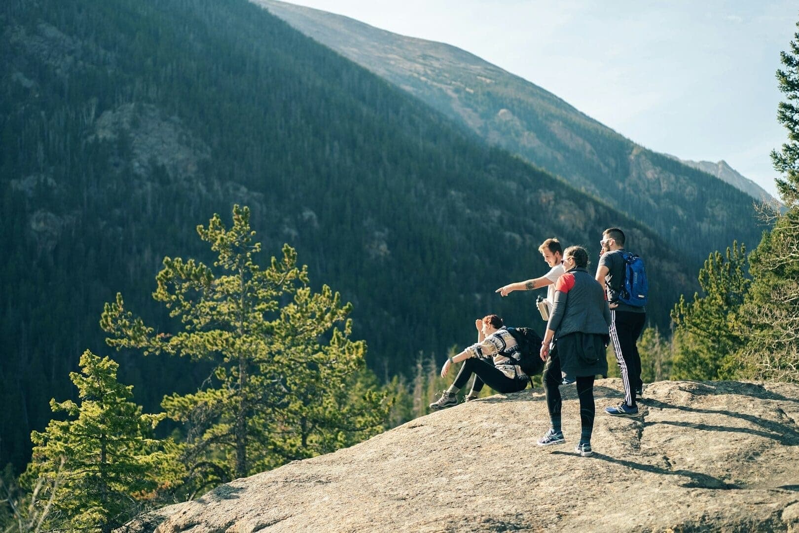 Group of four friends hiking and pointing at an overlook for brother birthday idea