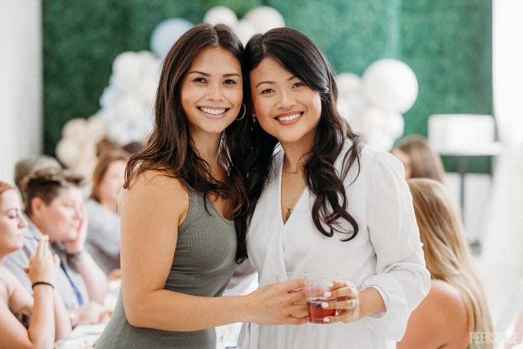 Friends smile and pose for the camera at a baby event