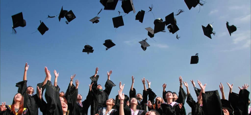 Graduates tossing caps into air.