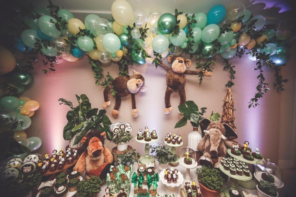 Stuffed monkeys, lions and elephants decorate a jungle-themed dessert table