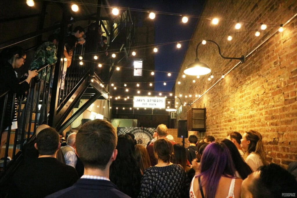 People gather in NYC alley under twinkly lights