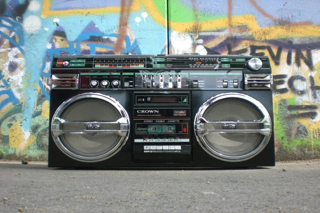 An old school boombox radio sits in front of a graffitied wall