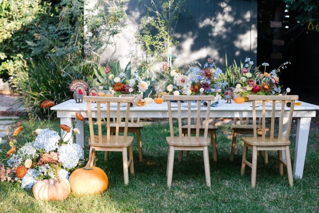 Outdoor dining table full of flowers and pumpkins