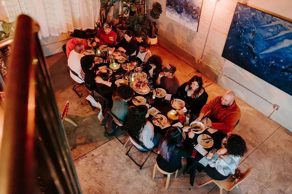 Aerial photo of friends celebrating at a decorated Friendsgiving table in an artsy Peerspace venue