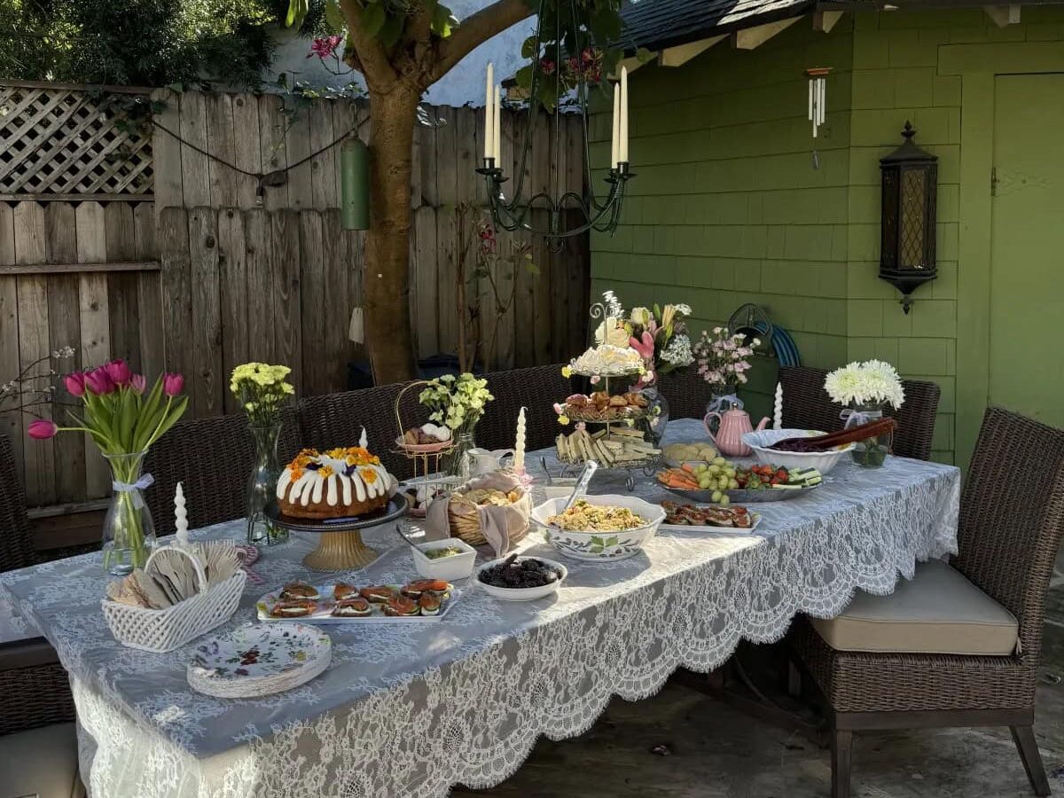 Outdoor table with Galentine's decor ideas, lace tablecloth, florals, and food