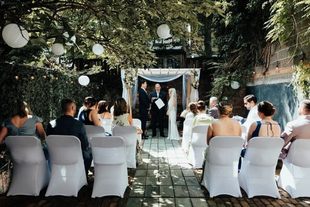 Couple getting married at small backyard wedding in Peerspace venue with chairs and guests