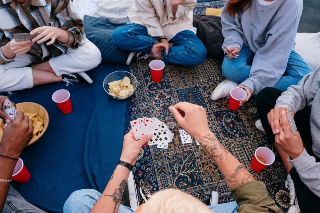 People sitting on picnic blankets with solo cups and cards