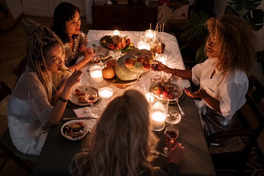 Photo from above of four friends around dinner table wearing Friendsgiving outfits
