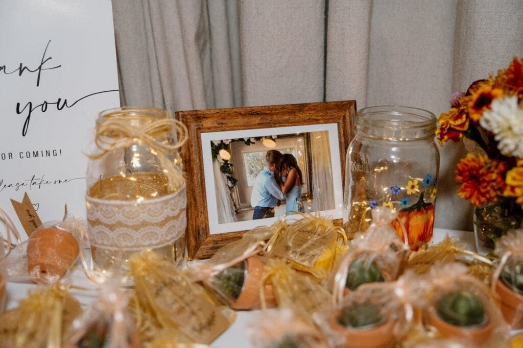 Table with budget wedding reception favors, framed photo, succulents