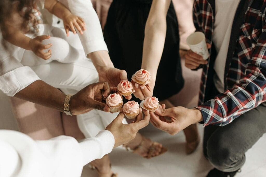 Group of people toasting with pink Galentines day themed cupcakes