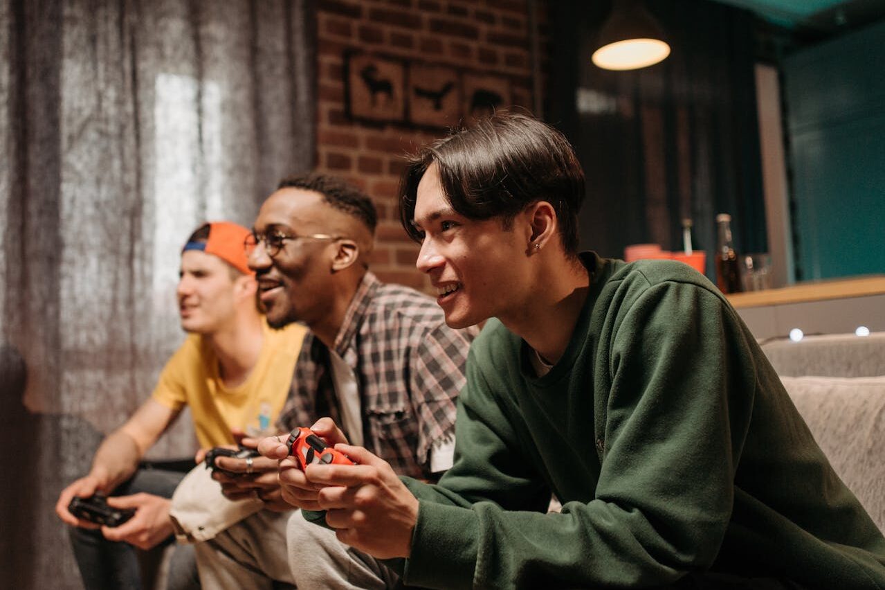 Three friends playing video games at as a birthday party idea for brothers