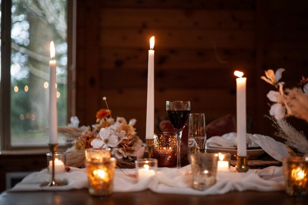 Rustic interior with candles, tablecloth, wine, and flowers on decorated fall-themed table