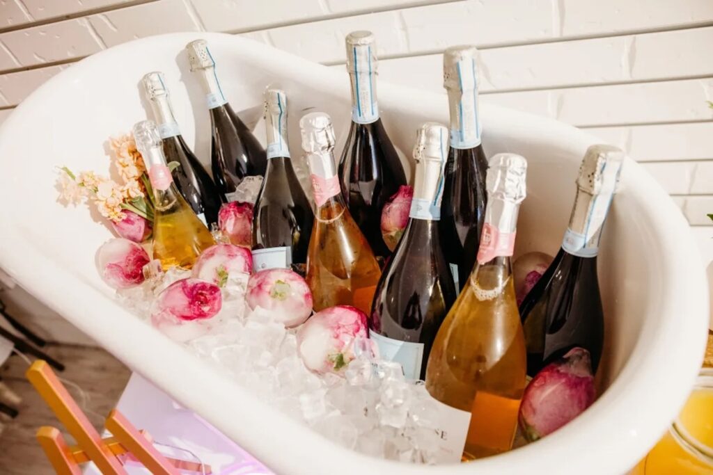 A bunch of bottles of champagne sit in ice in a small tub-shaped beverage container