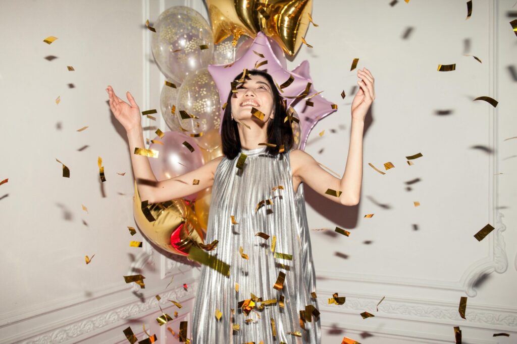 a woman in metallic dress with metallic balloons and confetti
